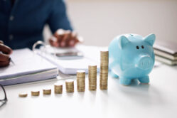 Man retirement planning with a piggy bank and stacks of coins on the table.