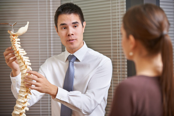 Chiropractor shows a patient a spine model