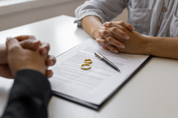 Divorce agreement papers with two rings sitting on top of them on a table.