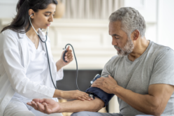 A doctor takes the blood pressure of a veteran, who has Tricare for Life.